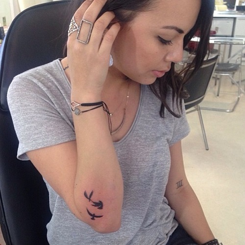 Janel Parrish's tattoos - flock of birds tattoo on right elbow